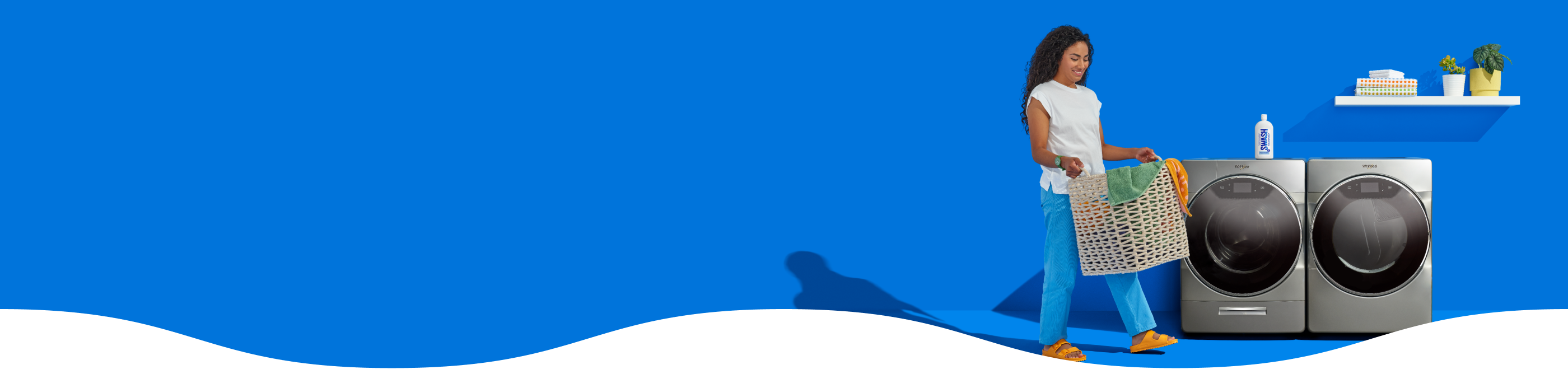 Woman carrying a basket of laundry infront of a Whirlpool® Washer and Dryer