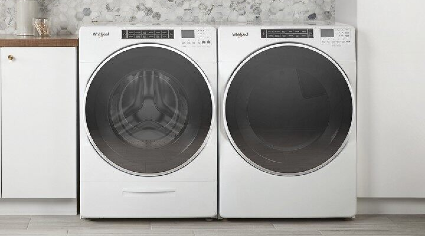 A front load Whirlpool® washer and dryer in a laundry room with white white cabinets