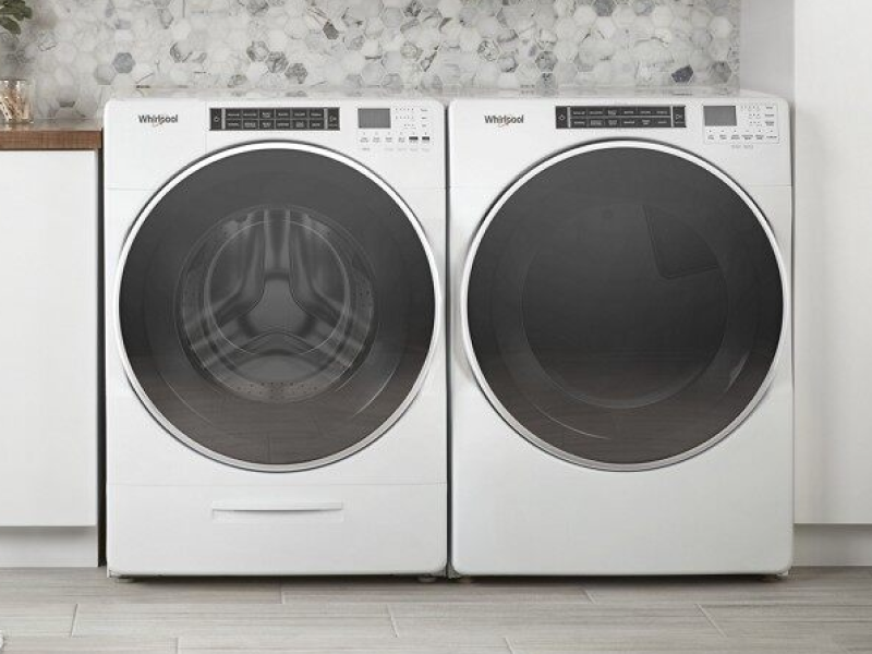 A front load Whirlpool® washer and dryer in a laundry room with white white cabinets