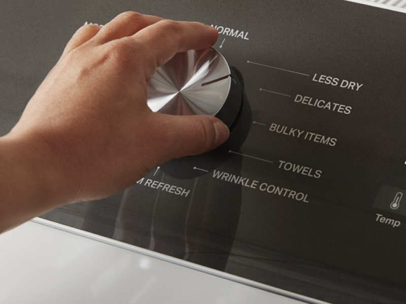 A person adjusts the dial on a Whirlpool dryer.