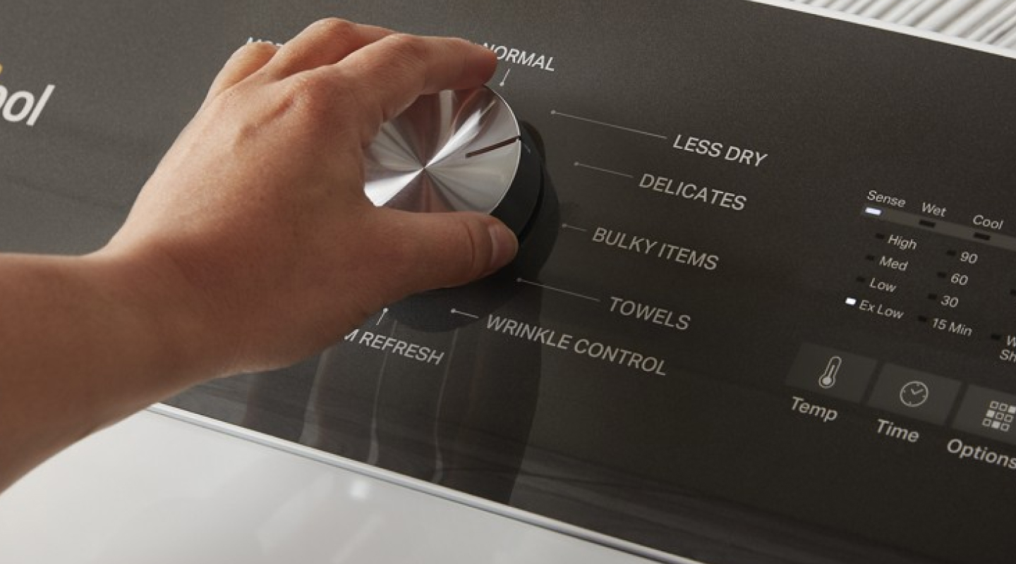 A person adjusts the dial on a Whirlpool dryer.