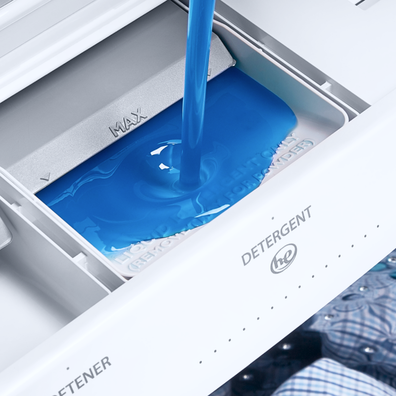 Blue liquid detergent being poured into a washing machine.
