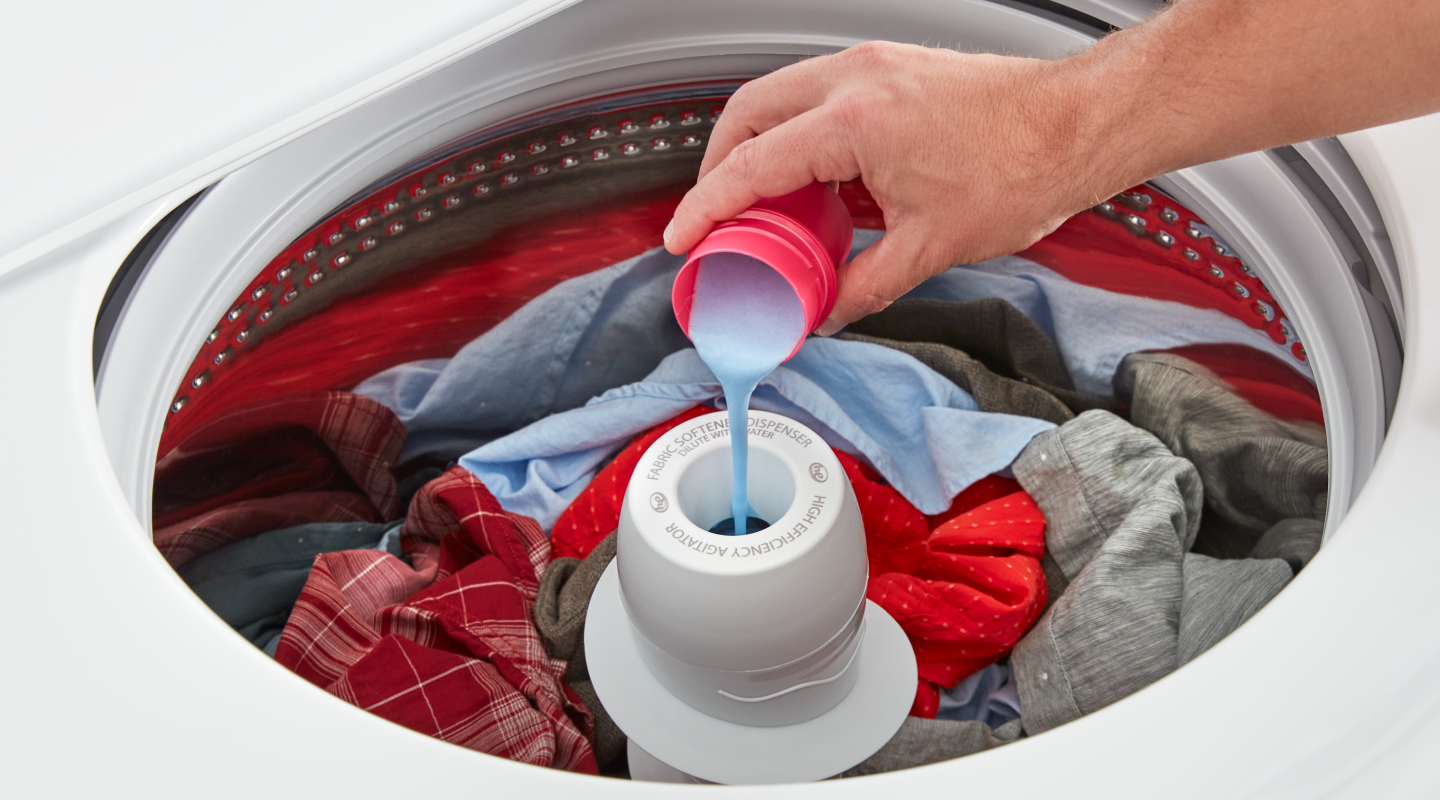 A person adding liquid detergent to a washing machine